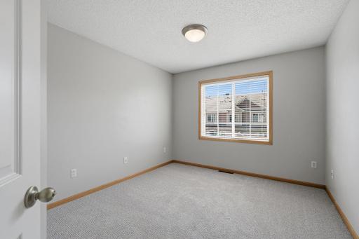 Located next to the primary suite, the second upper-level bedroom offers comfortable dimensions and a large window that brings plenty of natural light into the space.