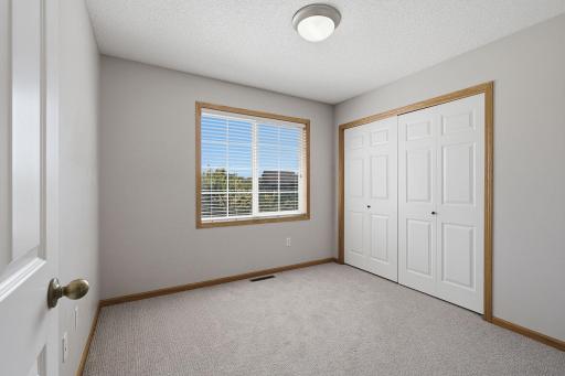 The third bedroom offers a bright and versatile space with generous closet storage and a large window overlooking the neighboring park and green space, adding a pleasant outdoor view.
