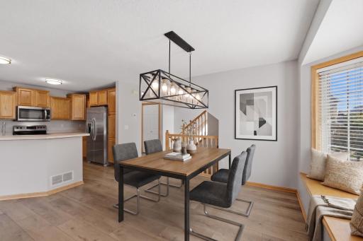 The dining area is highlighted by a modern statement chandelier, while the large bay window brings in abundant natural light and provides a bright backdrop for everyday dining or entertaining. - Virtually Staged