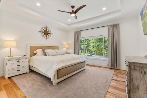 The large primary bedroom offers warm, yet luxurious finishes including the automatic window treatment, tray ceiling, beautiful flooring and attached en-suite