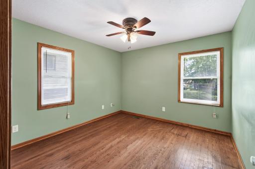 Main floor bedroom 2 with natural hardwood flooring.