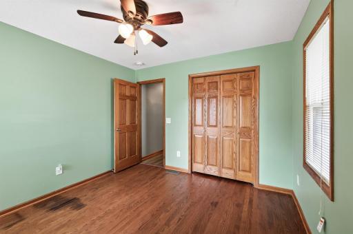 Main floor bedroom 2 with natural hardwood flooring.