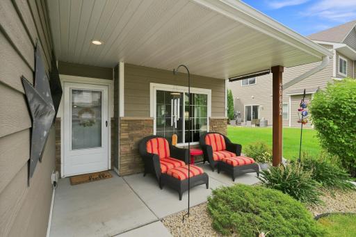 A Beautiful Covered Front Porch with Solid -Surface Siding and Stone Accents, Offering a Comfortable Space to Sit and Enjoy the Outdoors