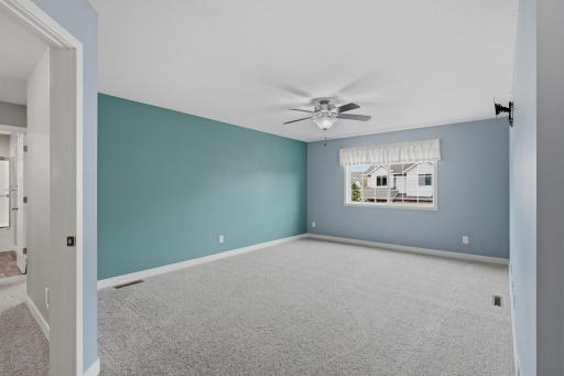 Spacious Primary Bedroom with a Ceiling Fan, Wall Mounted TV Bracket, and Plenty of Room for Your Bedroom Furnishings