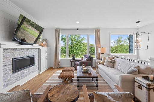 Oversized windows flood this living room with natural light while a gas fireplace with custom tile surround and built-in cabinetry create a warm, polished gathering space.
