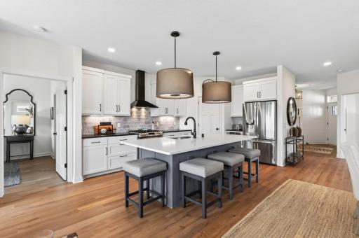 The details in this stunning chef's kitchen: gas range with griddle, custom enameled cabinetry, tile backsplash, black Soapstone surround, center island with sink, corner pantry with automatic lighting, coffee bar, and under cabinet lighting.