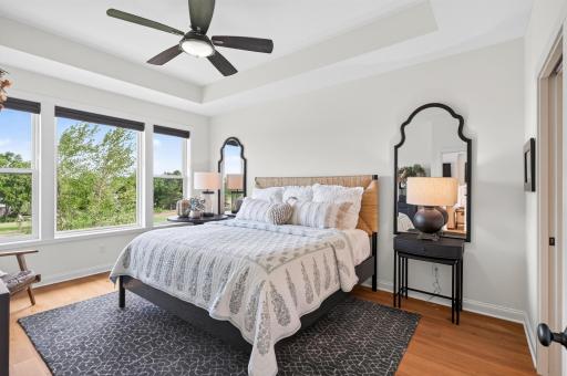 From the custom Hunter Douglas window treatments to the tray ceiling, oversized windows, fully tiled shower, dual sinks, walk-in closet, and wrap-around main-level laundry; this primary suite was designed for effortless, luxurious everyday living.