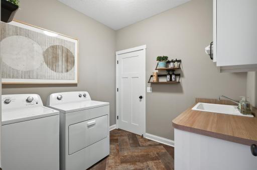 No hauling laundry up and down stairs. Thoughtfully designed, this main-level laundry room sits just steps from the primary closet and features a Whirlpool washer and dryer, laundry sink, and extra cabinetry for everything you need.