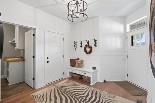 Whether guests arrive through the front door or the garage, this inviting entryway makes a stunning first impression: a custom built-in bench with storage, designer wrought iron hooks, and a dedicated mudroom closet with automatic lighting.
