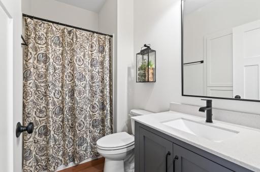 A beautifully appointed full bathroom on the main level for guests that is complete with a clever built-in linen closet tucked behind the door for smart, hidden storage.