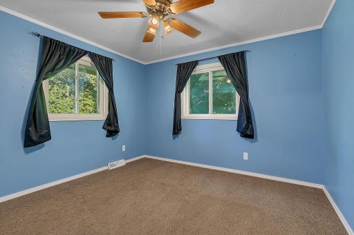 Hereâs a look at the second upper-level bedroom, featuring multiple windows for great natural light and a ceiling fan for added comfort.