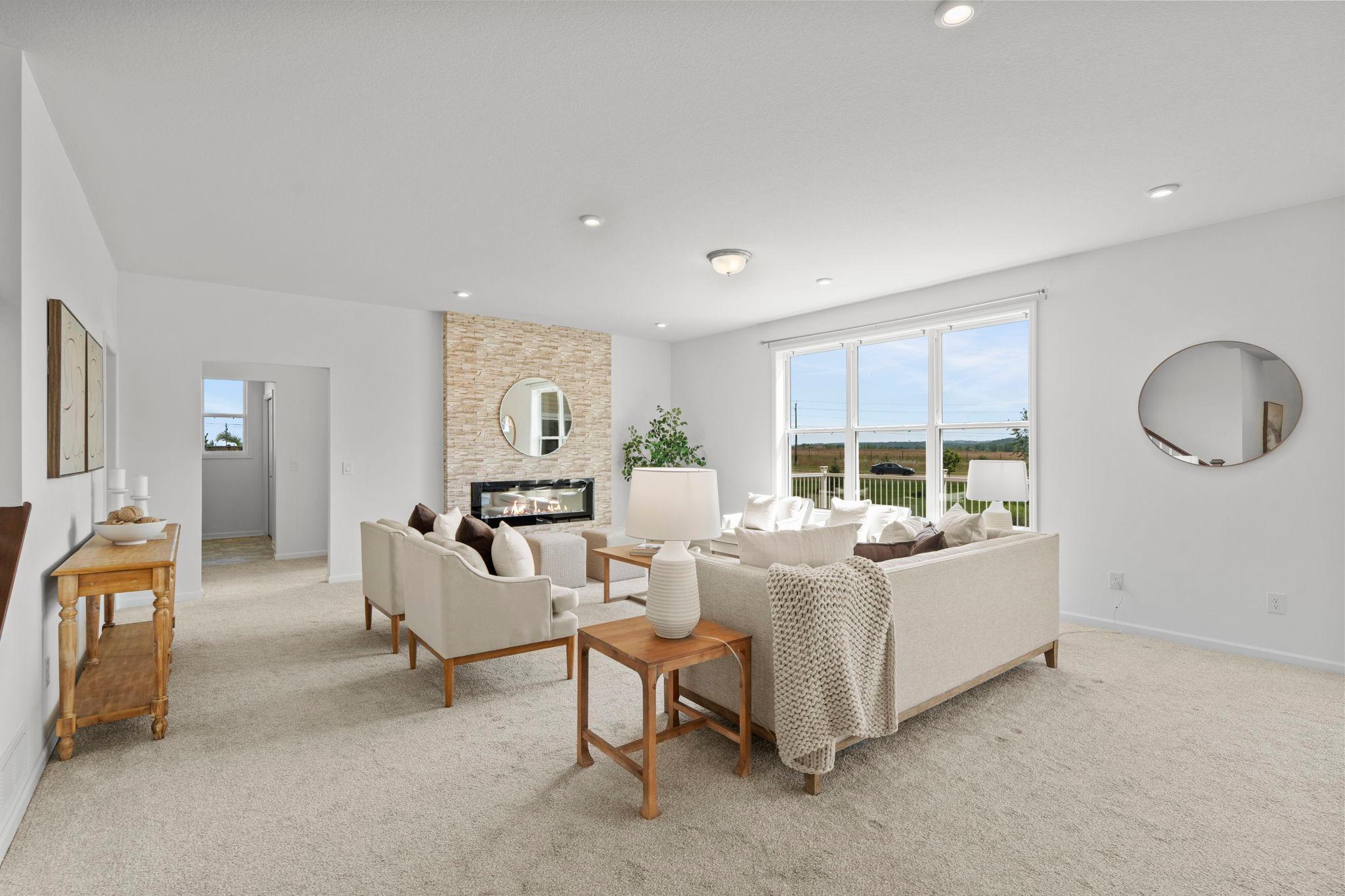 Elegant living room centered around a beautiful gas fireplace, complemented by a dramatic oversized window that floods the space with natural light and highlights the room’s warm, inviting atmosphere.