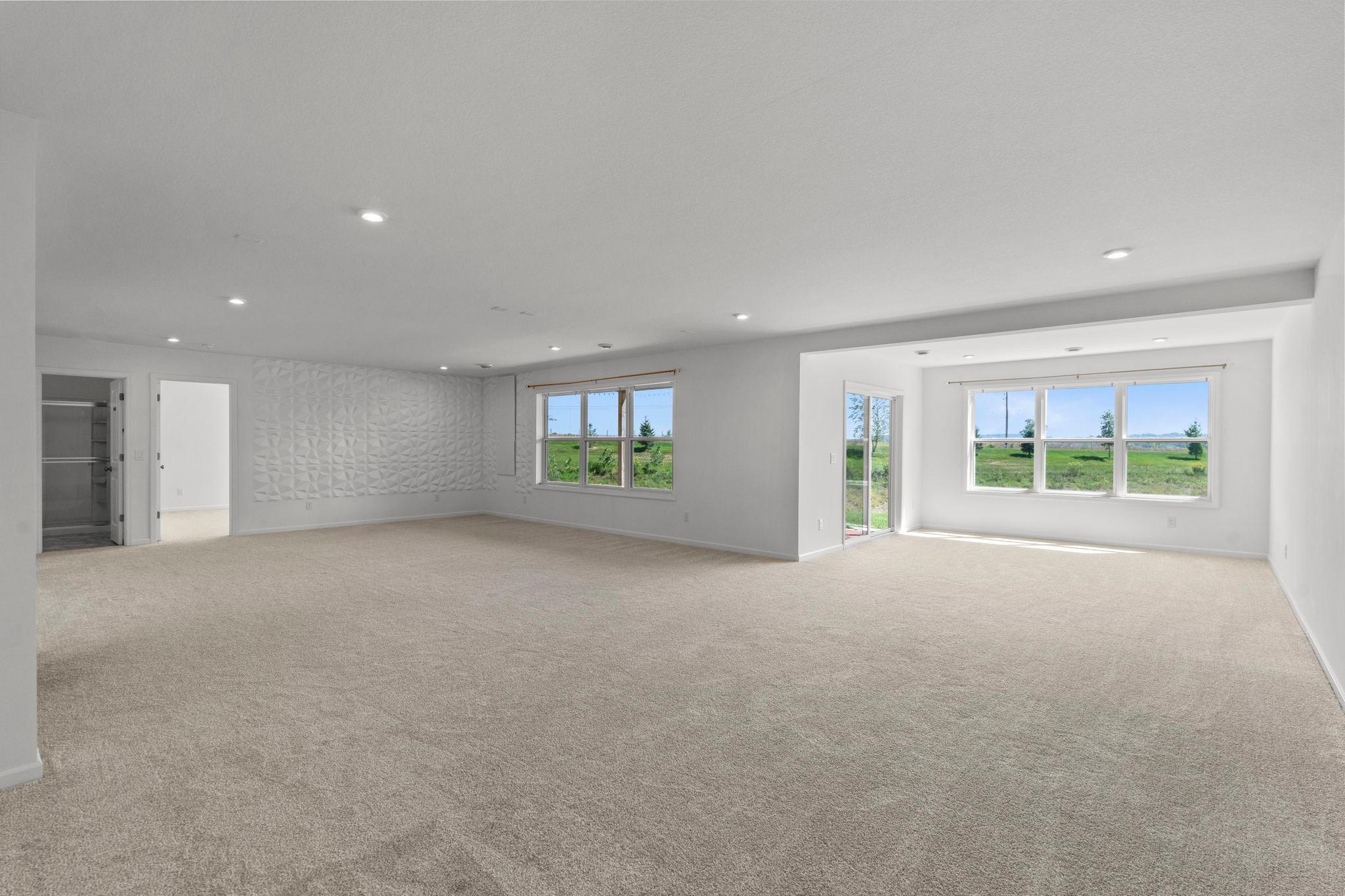 Spacious walkout lower level featuring a 3D accent wall, Alexa-controlled lighting, and a bright, inviting sunroom