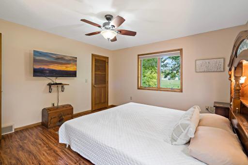 Spacious primary suite features warm wood tones, wide windows overlooking the yard, and generous closet storage
