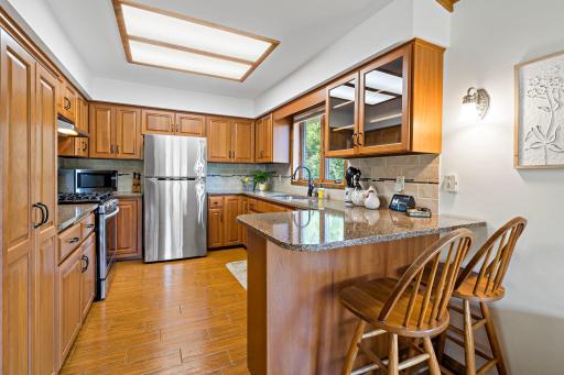 Well-appointed kitchen features stainless steel appliances, granite counters, and a breakfast bar with seating for two