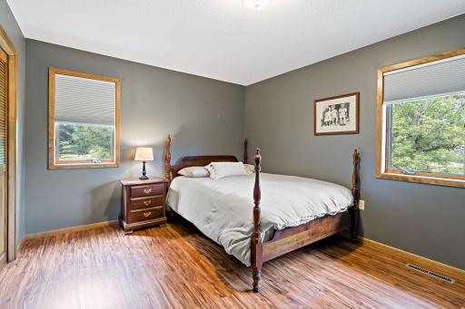 Second bedroom offers a moody, sophisticated palette with dual windows bringing in leafy, wooded views