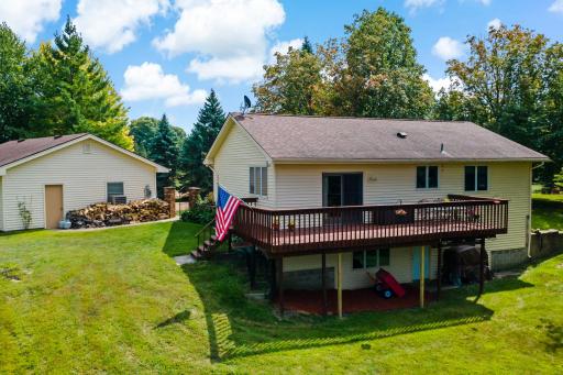 Aerial view showcases the walkout lower level, expansive deck, all set on a private, tree-lined lot