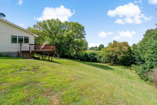 Rolling backyard offers space to roam and a natural tree line for added privacy, with rural views stretching beyond