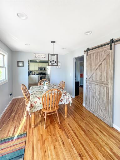 The dining room is filled with natural light and accented by warm hardwood flooring and a barn door.