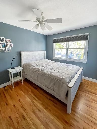 Comfortable secondary bedroom with hardwood floors, neutral finishes and natural light.