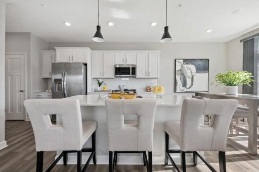 (Photo of a decorated model, actual features will vary) The spacious kitchen features a large center island, quartz countertops, recessed lighting, under mount sink, LVP floors, stainless appliances and more!