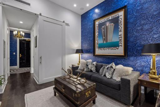 A custom sliding barn door allows the den to function beautifully as a private second bedroom when desired. Designer wallcovering, a Samsung Art TV and integrated Sonos surround sound give this flexible space a distinctly finished feel.