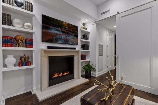 Custom JW Woodcraft floating bookshelves add architectural interest and functional display space. A 40-inch Dimplex Opti-myst fireplace adds the visual warmth of a fireplace with an integrated water-fed system for convenient automatic refill.
