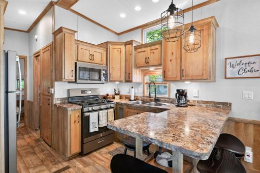 Efficiently designed to maximize space and warmth, this rustic cabin kitchen pairs modern stainless steel appliances with natural wood craftwork and stylish contemporary lighting.
