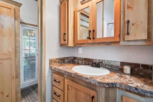 Clean and functional, this bathroom vanity area highlights smart storage and warm inspired finishes.