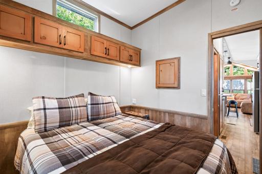 Windows on two sides bring in natural light, including an upper transom window above the bed cabinets and a side window framed in matching wood trim.