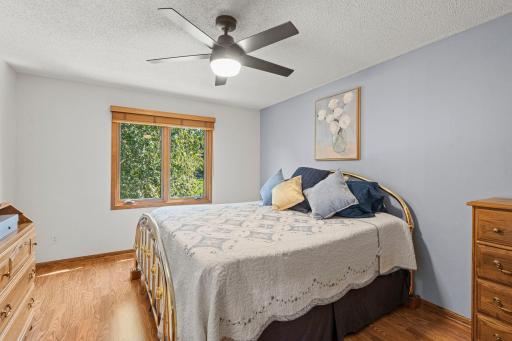This comfortable bedroom offers calming colors, natural light and serene views of the mature trees outside.