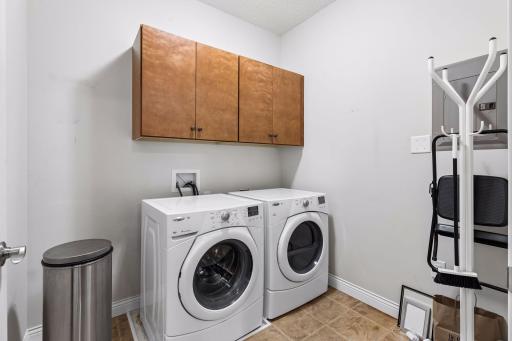 Laundry is located off kitchen with cabinets and room to keep vacuums and mops