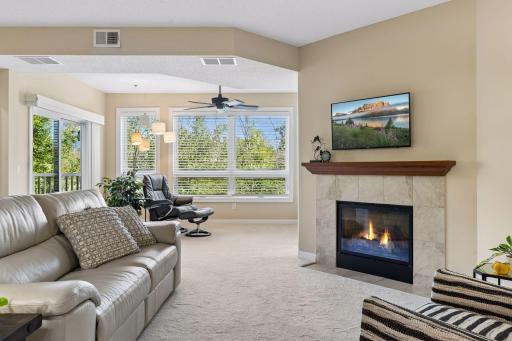 Open living room to sunroom with lots of windows and private views. Gas fireplace surrounds by ceramic tile and cherry mantle.