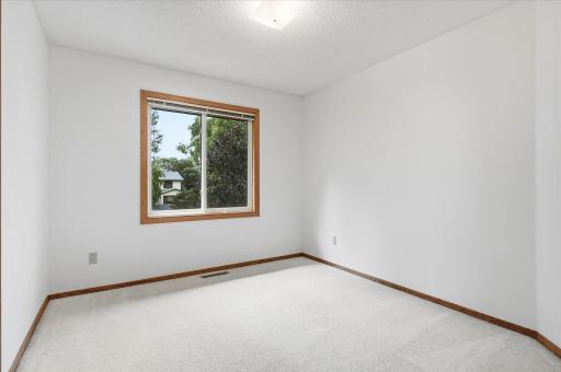 Generously sized second bedroom with a large window and plenty of flexibility for furniture placement.