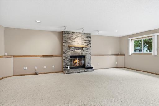 The striking brick wood-burning fireplace positioned in the center of the lower-level family room creates a warm, inviting focal point while adding character to the spacious entertaining area.