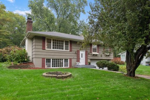 A second exterior view highlights the homeâs classic bi-level design, mature trees and spacious setting.