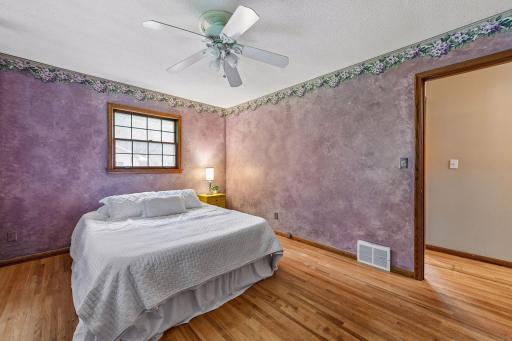 Spacious primary bedroom features original red oak hardwood floors, two windows and plenty of room for additional furniture.