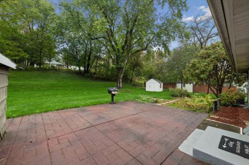 Expansive brick patio with room to dine, grill and entertain, surrounded by a beautifully spacious, tree-lined yard.