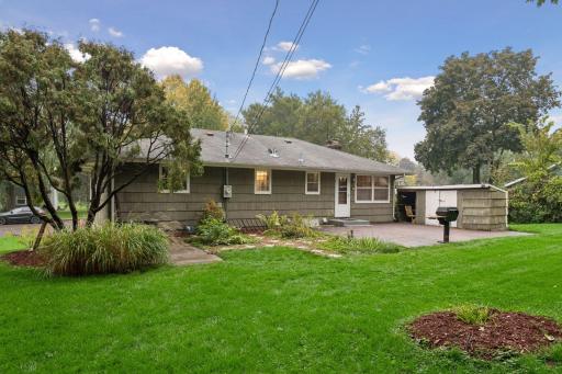 Brick patio and garden beds create a welcoming outdoor living space overlooking the expansive yard.