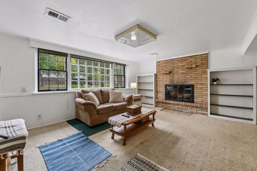 The finished lower-level family room offers great natural light, a second brick fireplace and built-in shelving for added character.