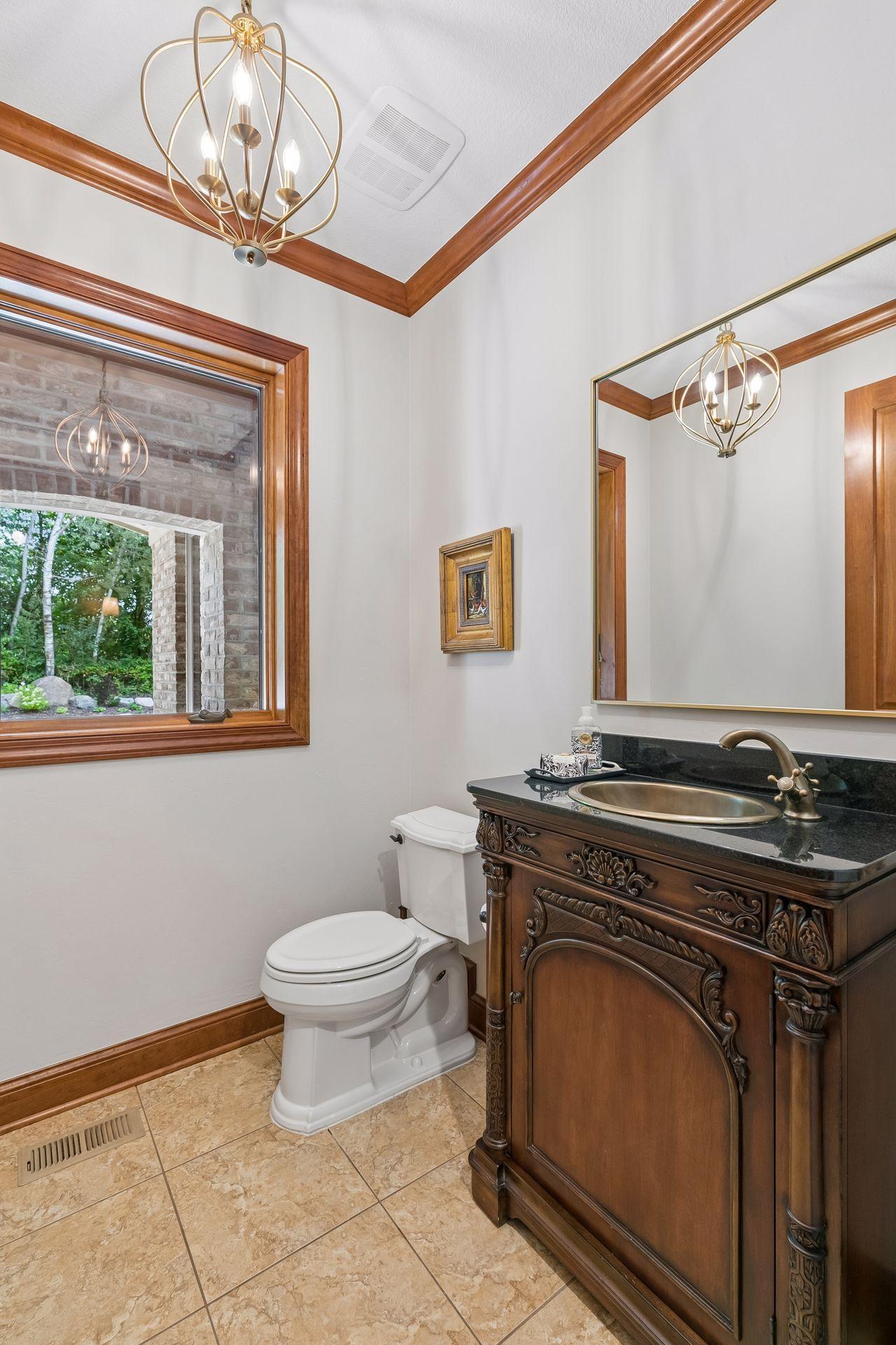 Half bath on main level adorned with a free-standing cabinet and brass sink and faucet