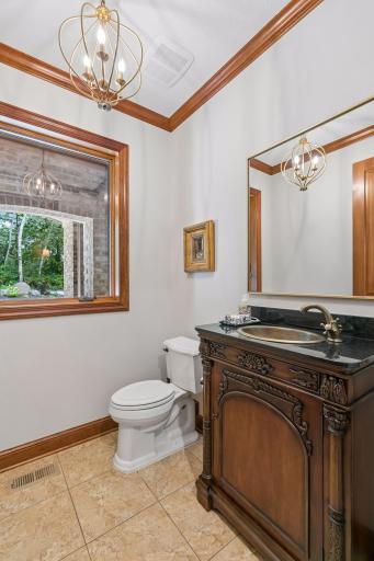 Half bath on main level adorned with a free-standing cabinet and brass sink and faucet