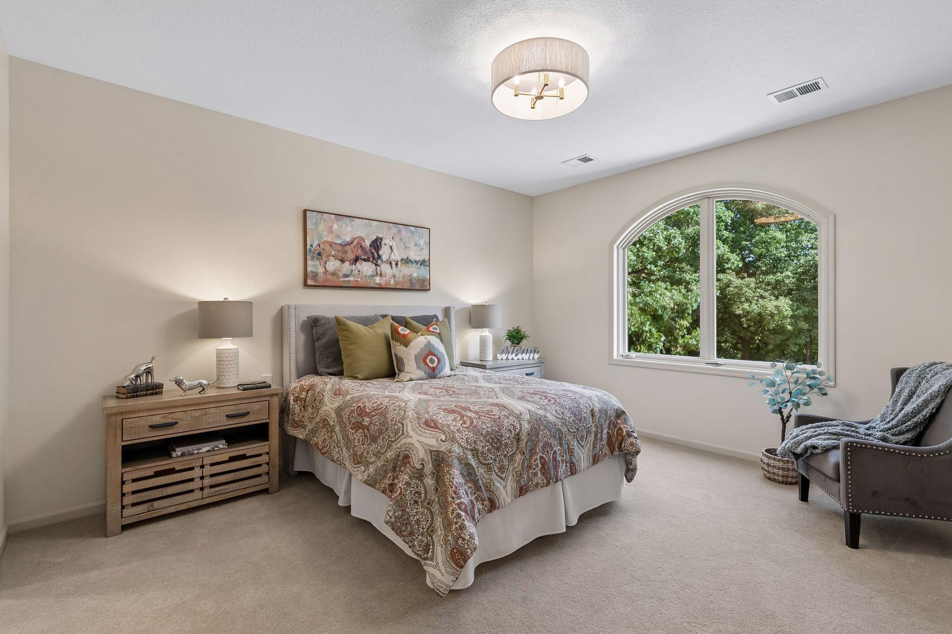 Second bedroom with ensuite on the upper level with arched window overlooking the front treed yard