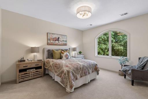 Second bedroom with ensuite on the upper level with arched window overlooking the front treed yard