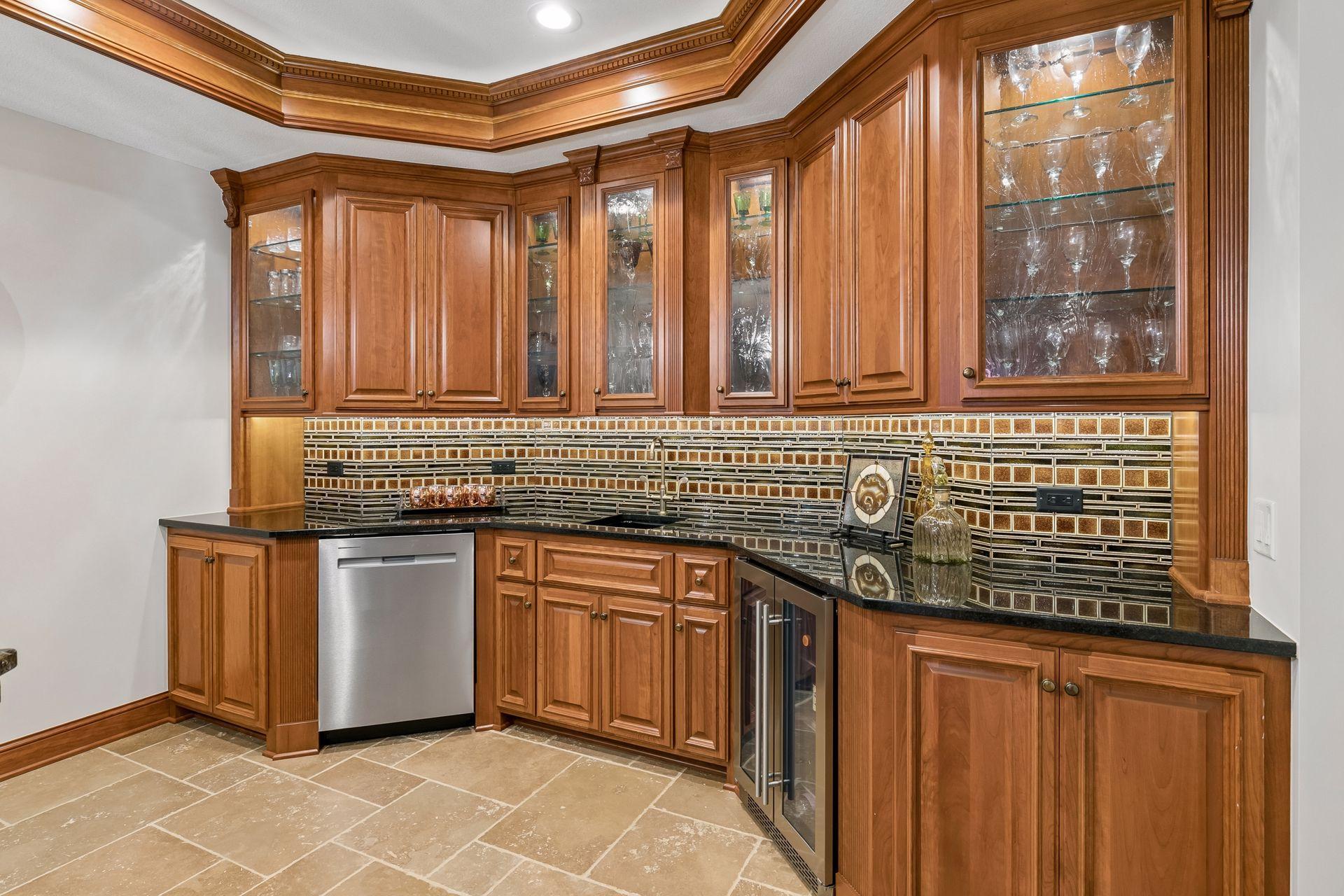 The wet bar features granite surfaces, custom tile backsplash and cove ceiling