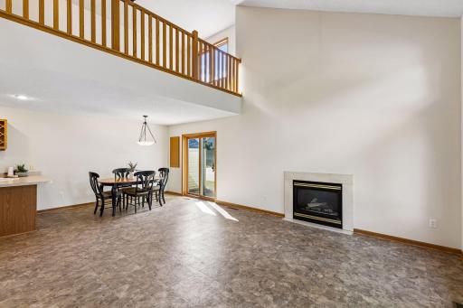 Open-concept living and dining area with soaring ceiling, gas fireplace and sliding door to the outdoor space.