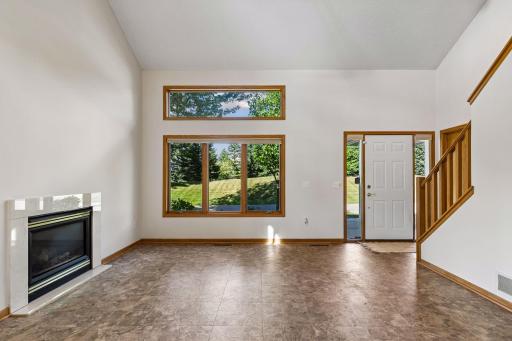 Bright, vaulted living room featuring expansive windows, a gas fireplace with stone surround.
