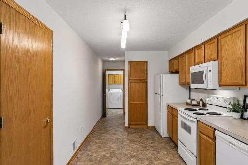 Kitchen with abundant cabinetry and counter space, plus conveniently located main-level laundry just beyond.