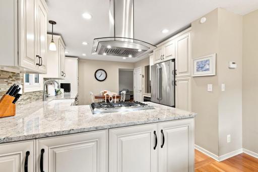 Large center island with gas cooktop and stone countertops
