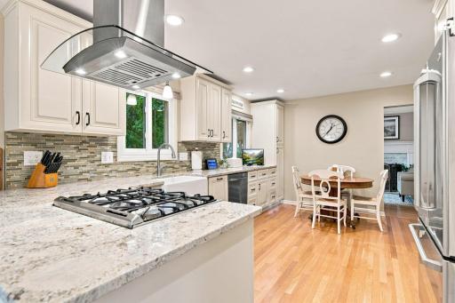 Gourmet kitchen featuring stone countertops, farmhouse sink and stainless steel range hood